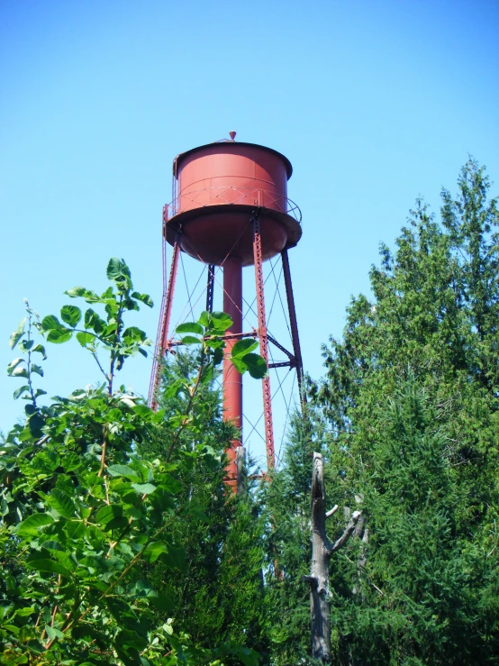 a metal water tower in front of some trees