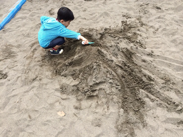 a  crouches in the sand and writes with his hand