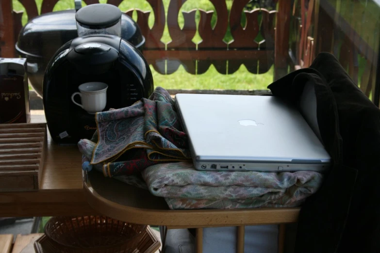 a laptop is on the table outside by a tea pot