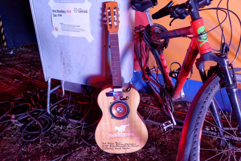 a guitar leaning against a bicycle's rear wheel