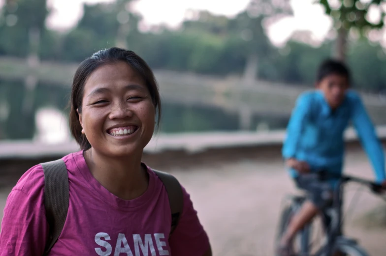 a woman is smiling in front of a boy on a bicycle