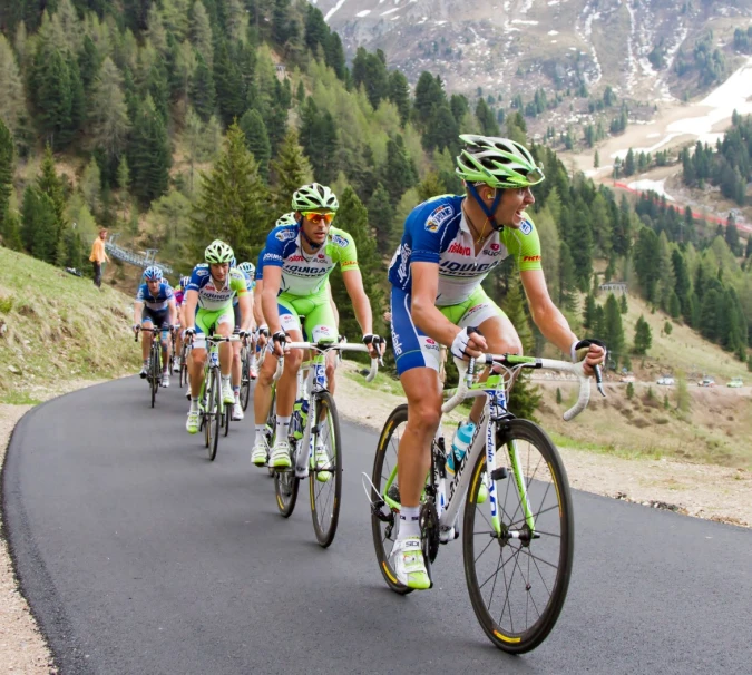 several bicyclists are riding along the road together