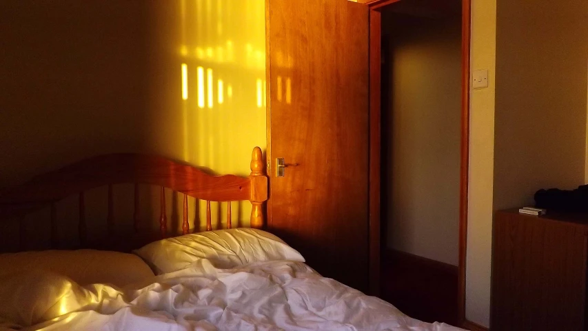 this bedroom is dark, light, and has sunlight coming in from behind a door