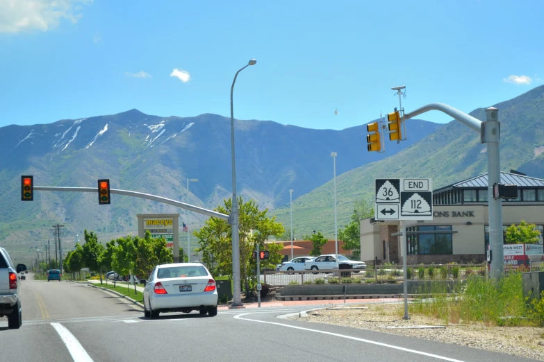 a traffic light suspended over a street next to tall mountains