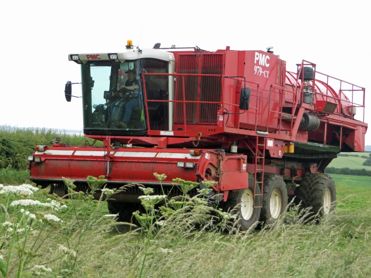 large red harvest machine in a green field