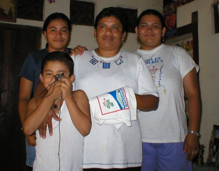 four women holding a little boy, and taking a picture