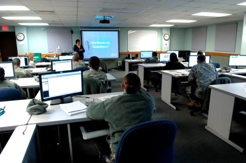 men are working at computers in a room with four screens