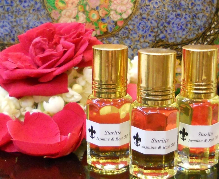 three bottles are next to a red rose and other flowers