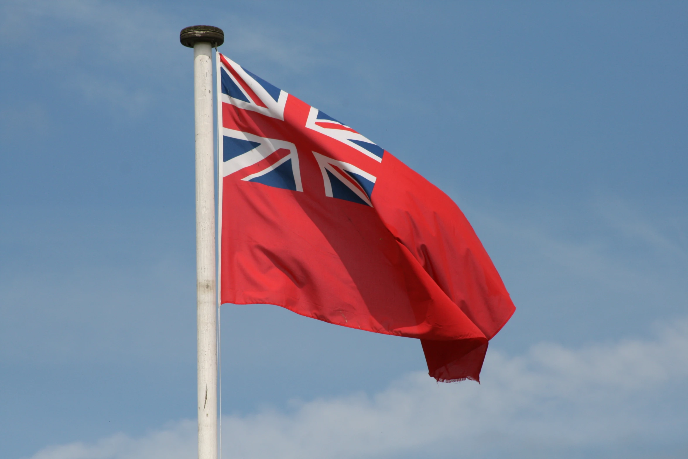 a big flag with a sky background on a pole