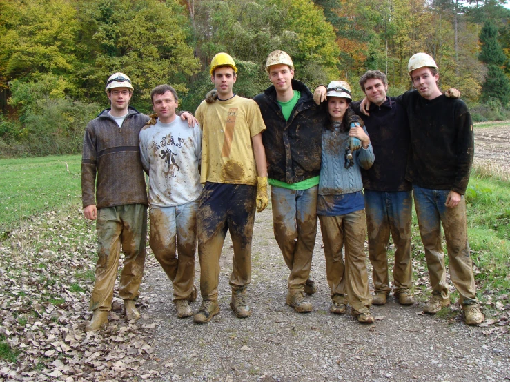 group of friends posing for po in muddy field