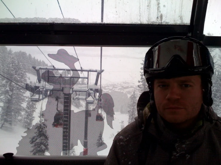 a man wearing goggles and a helmet is riding a ski lift