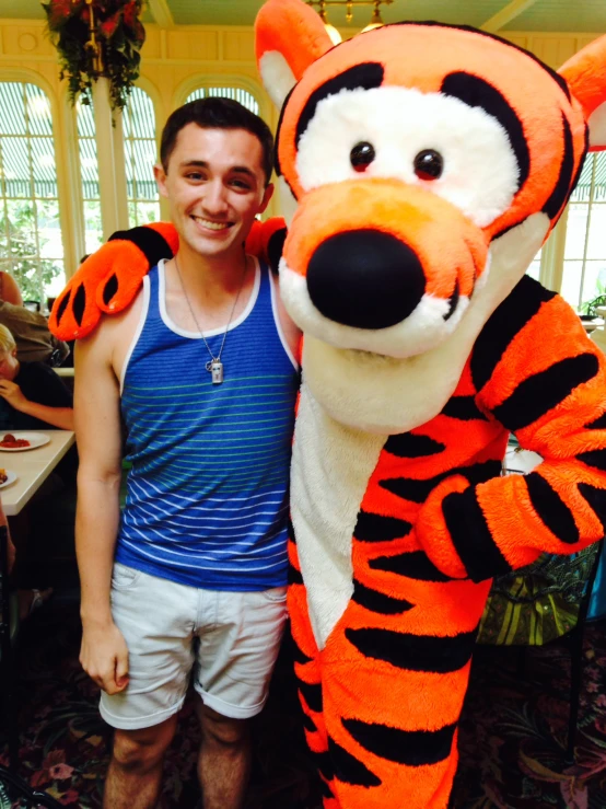 man standing next to tiger mascot, smiling