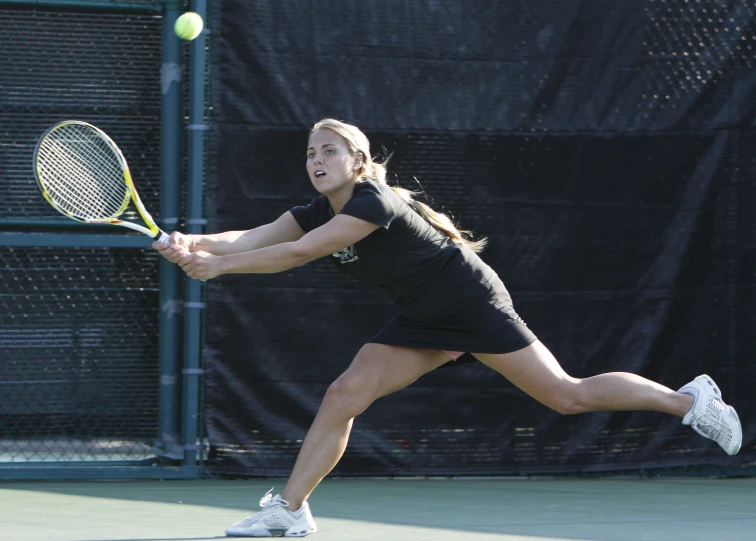 a young woman holding a tennis racquet near a ball