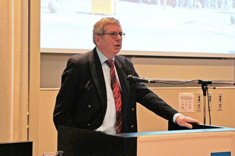 a man in a suit and tie talking at a podium