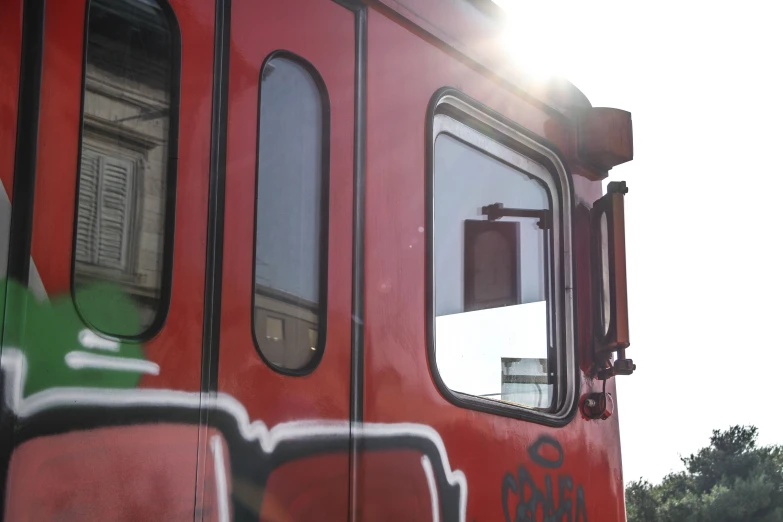 a red train covered in graffitti and sun