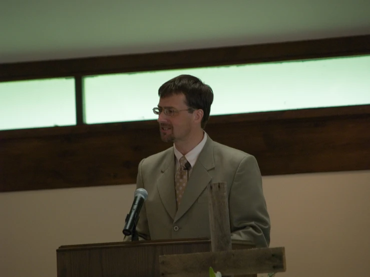 a man standing at a podium with microphone up to his side