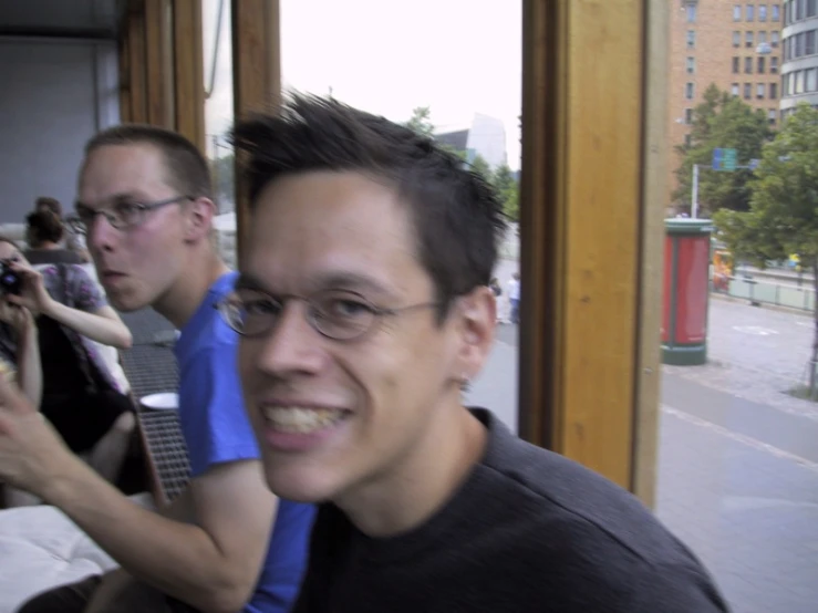 two men sitting next to each other in front of a window