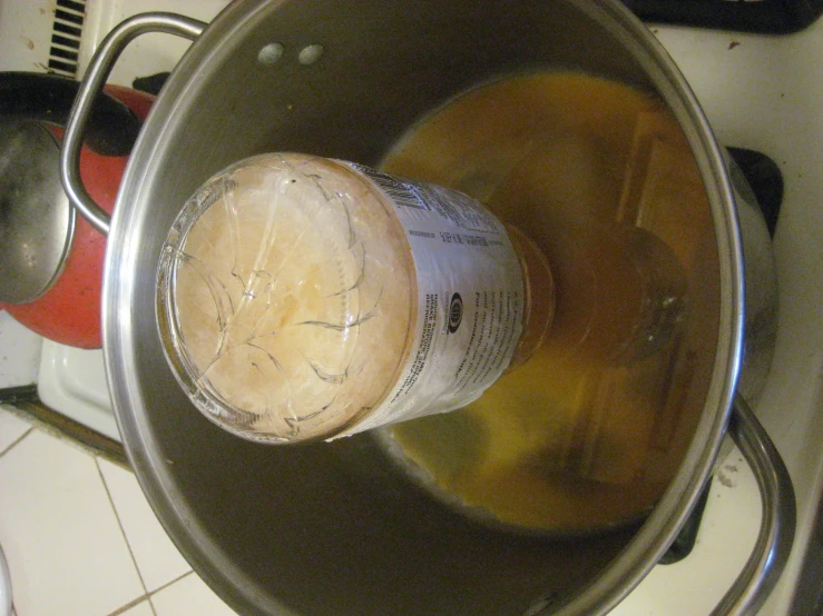 a bottle of beer sits inside of a pot on the stove