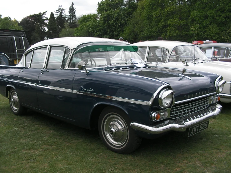 several classic cars parked on the grass in a row