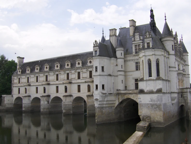 an old castle is next to water and its walls are reflecting the sky