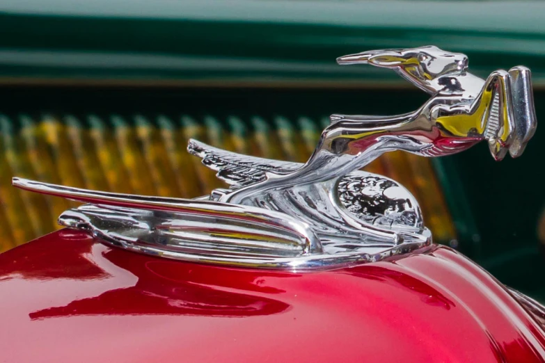 an old vintage red car with a chrome emblem