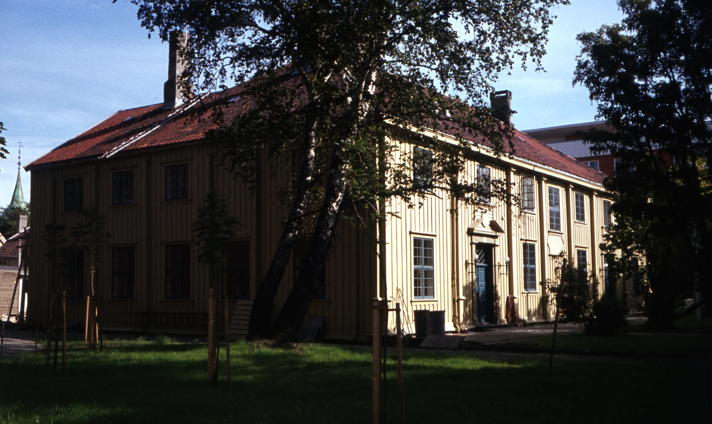 an old brown building in the middle of green grass