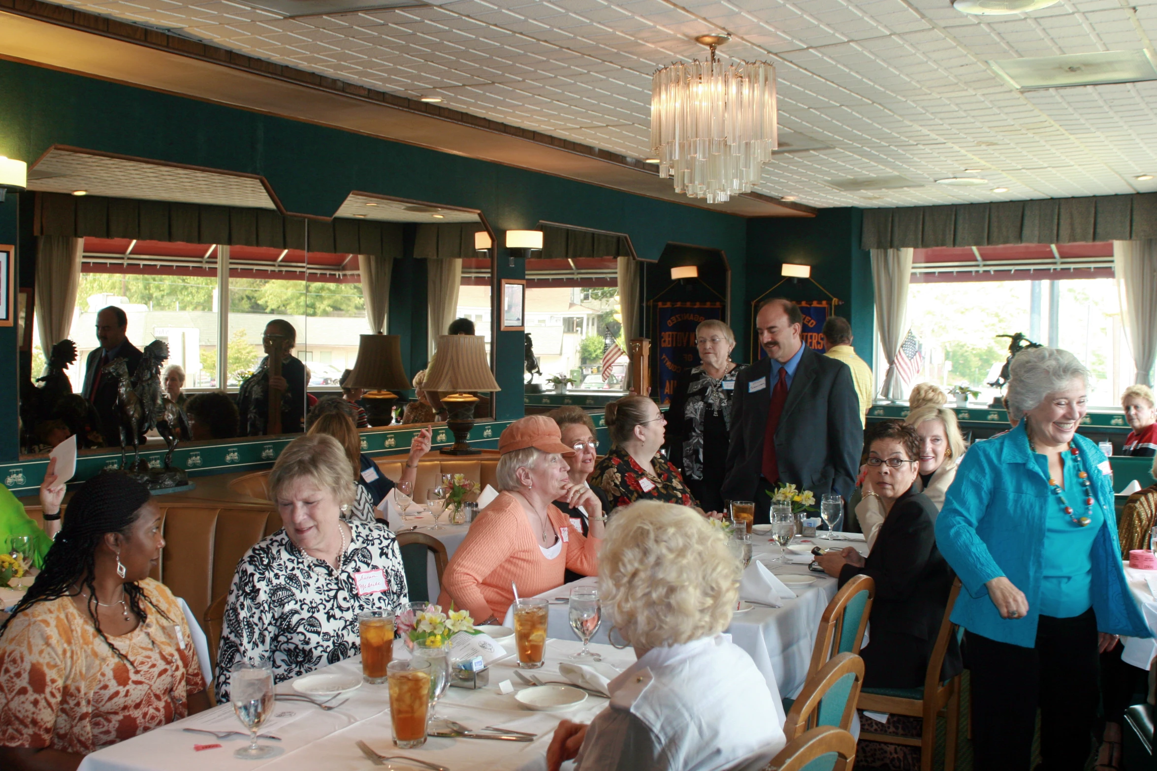 some elderly people dining in a restaurant while others look on