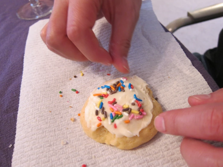 a hand reaching for some confetti on top of a cookie