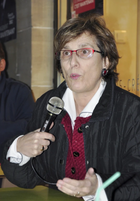 a woman holding a microphone and wearing glasses