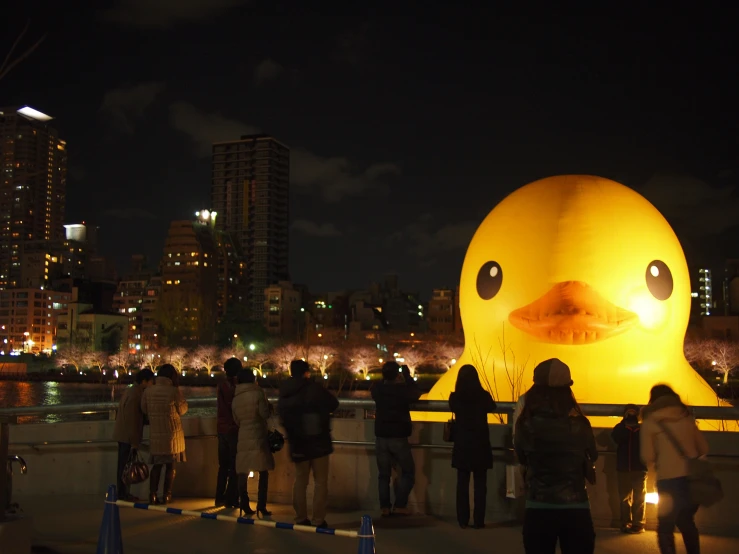 people are standing on the bridge beside an inflatable rubber duck