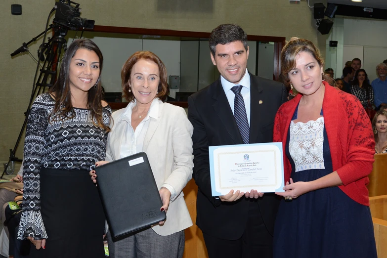 a woman is holding an award plaque while three people are standing beside her