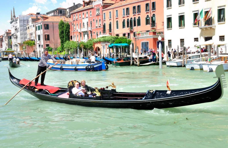 several people in a gondola in the water near buildings