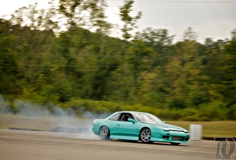 a teal colored car with some smoke