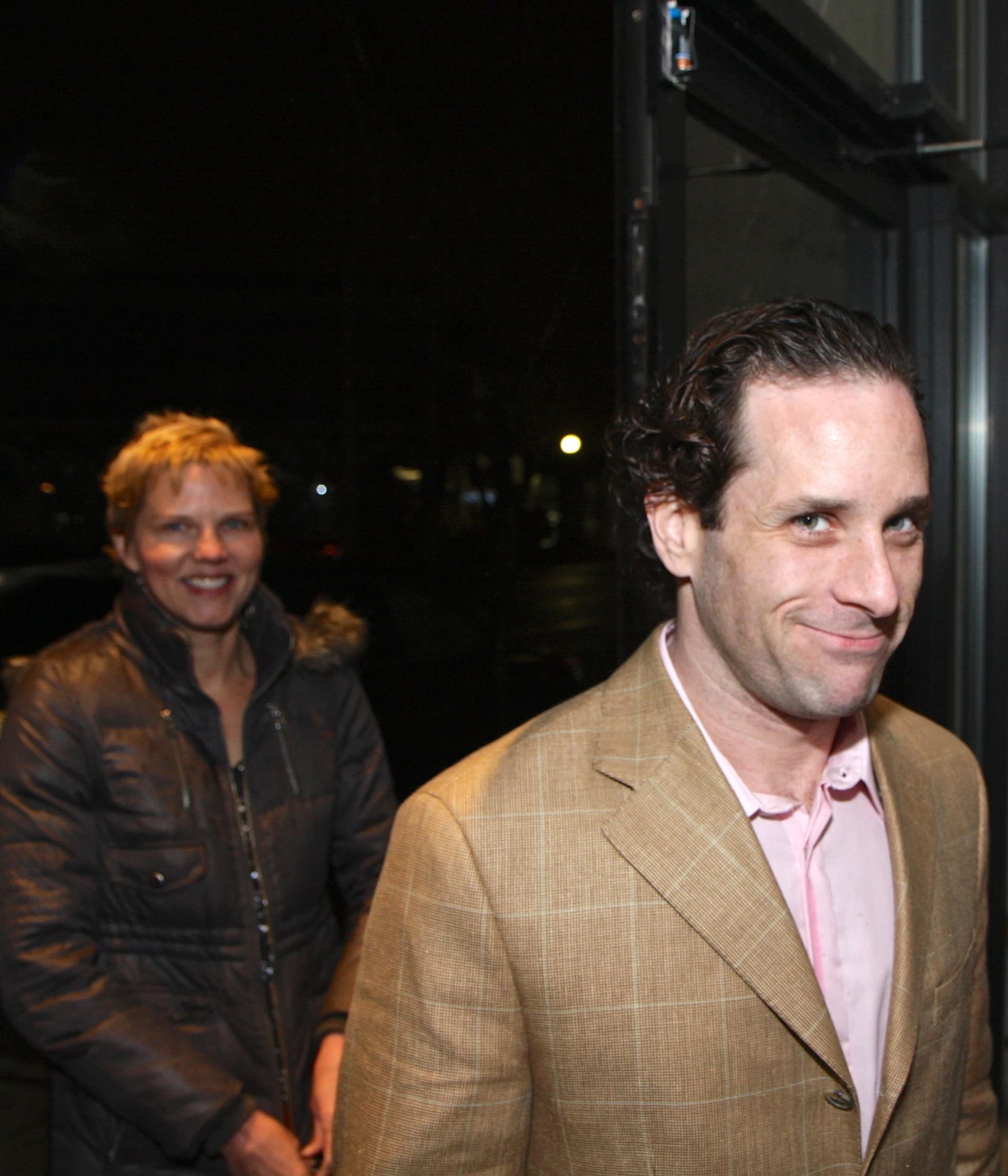 two people smile for the camera while outside at night