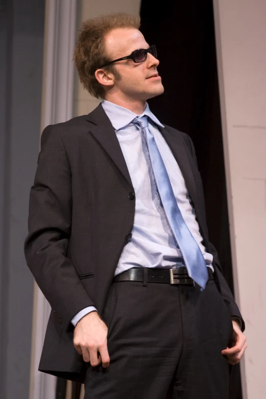 a man in business attire is standing with his hands in his pockets