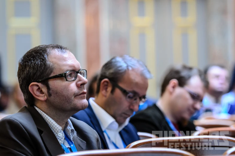 men sitting at a conference in a room with other men