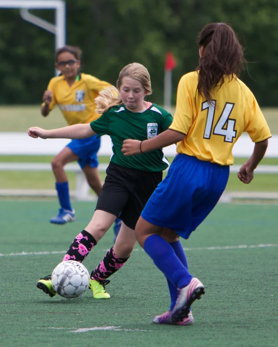 two girls who are playing soccer on a field