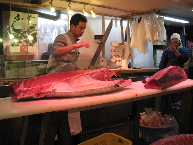 a man standing at a butcher's counter  up a large tuna