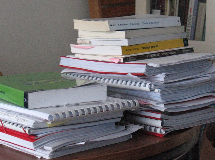 piles of books on a table near a clock