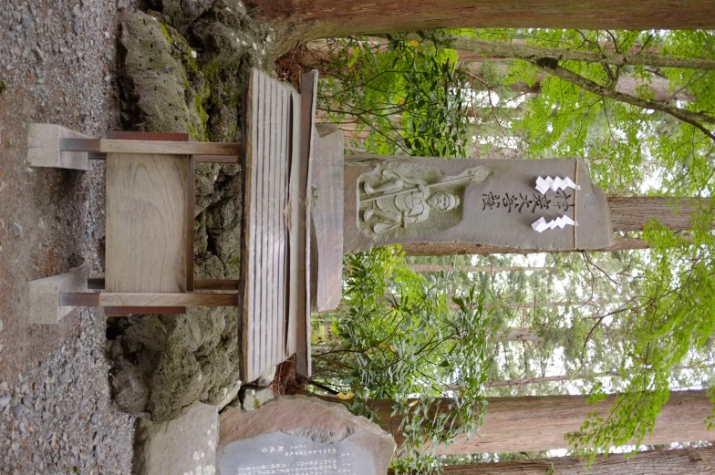 a wooden table sitting next to stone rocks and trees