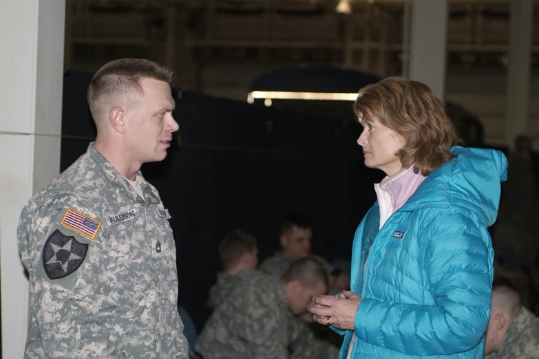 military man in camouflage jacket talking to woman in uniform