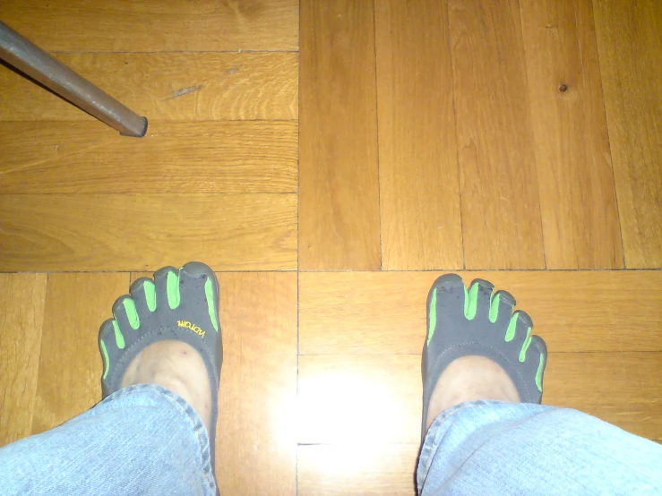 feet with rubber shoes standing near wooden floor