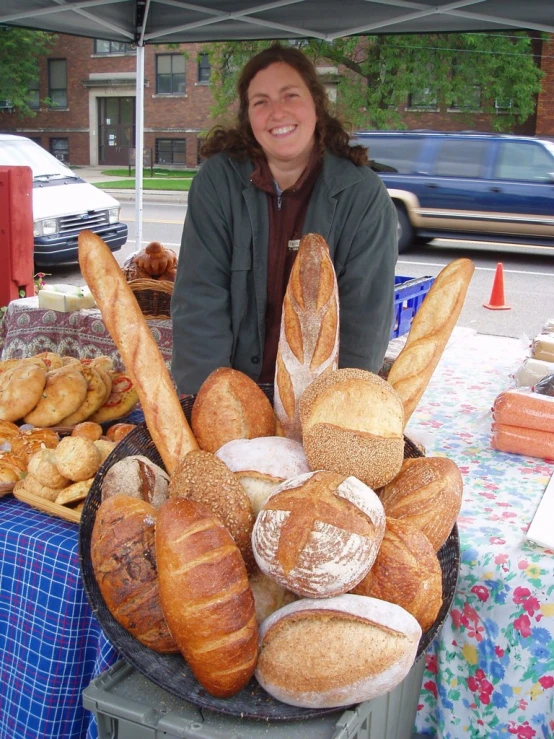 there is a woman standing next to many breads