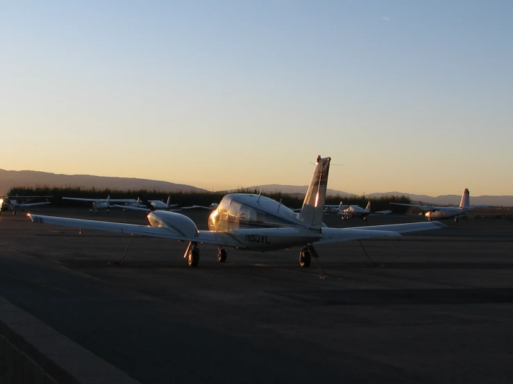small white airplane parked in an airport at sunset