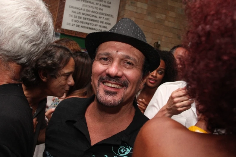 a man in a black shirt and hat smiling