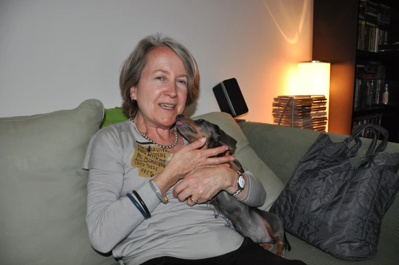 a woman holding a small dog on top of a green couch