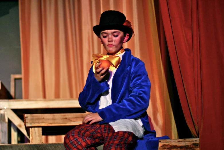 young male in blue and red outfit and hat eating an apple