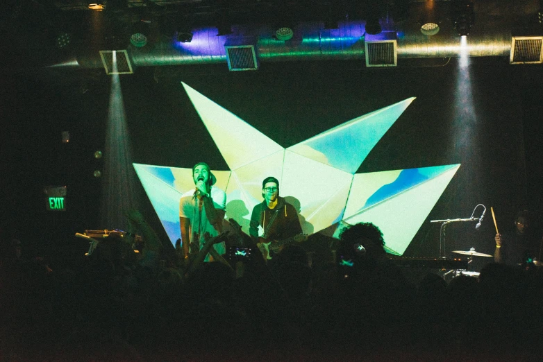 people are sitting on a stage with light beams in the background