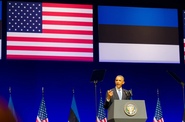 the president gives a speech to a group of us flags