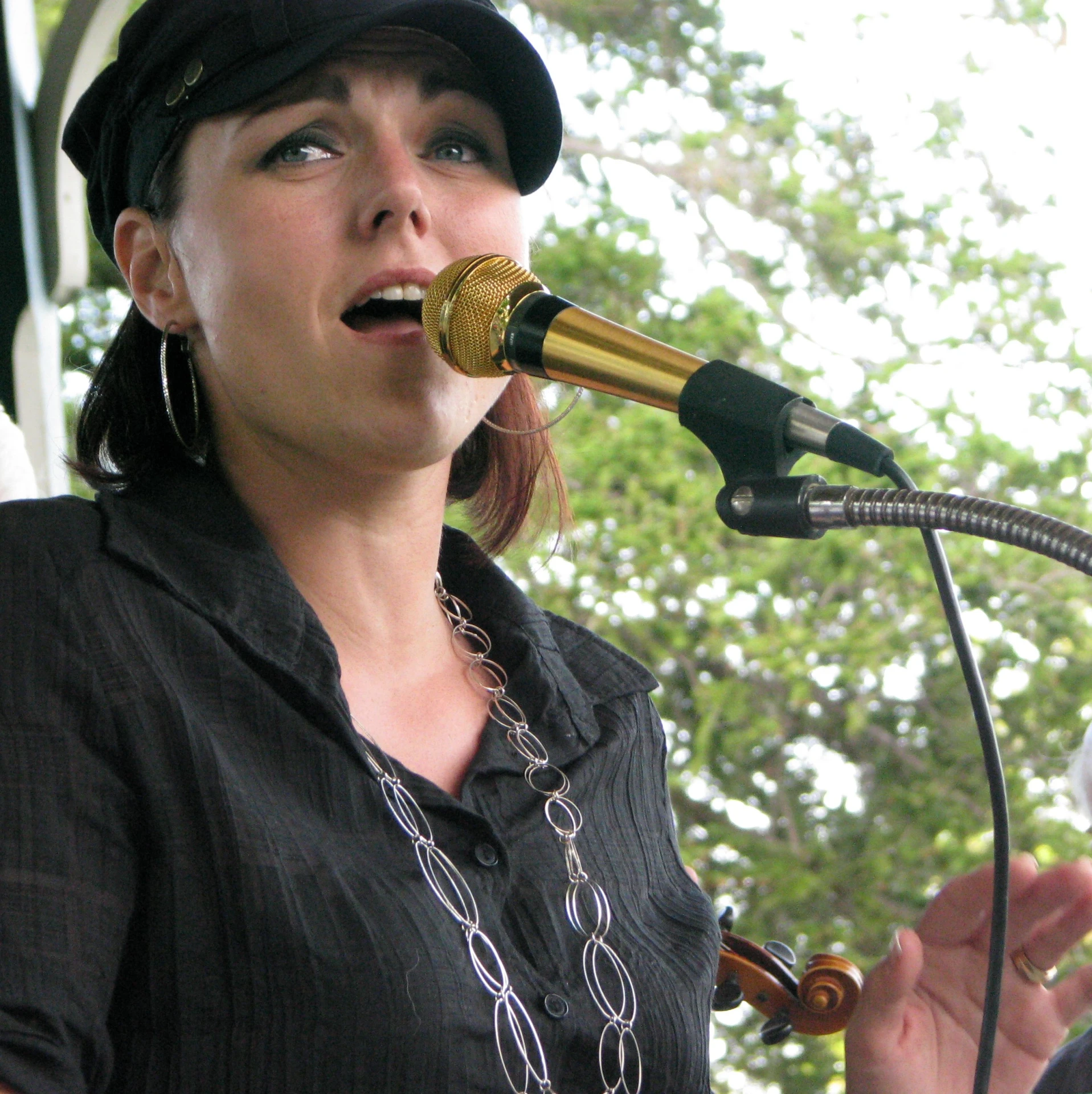 a woman singing into a microphone with a hat on